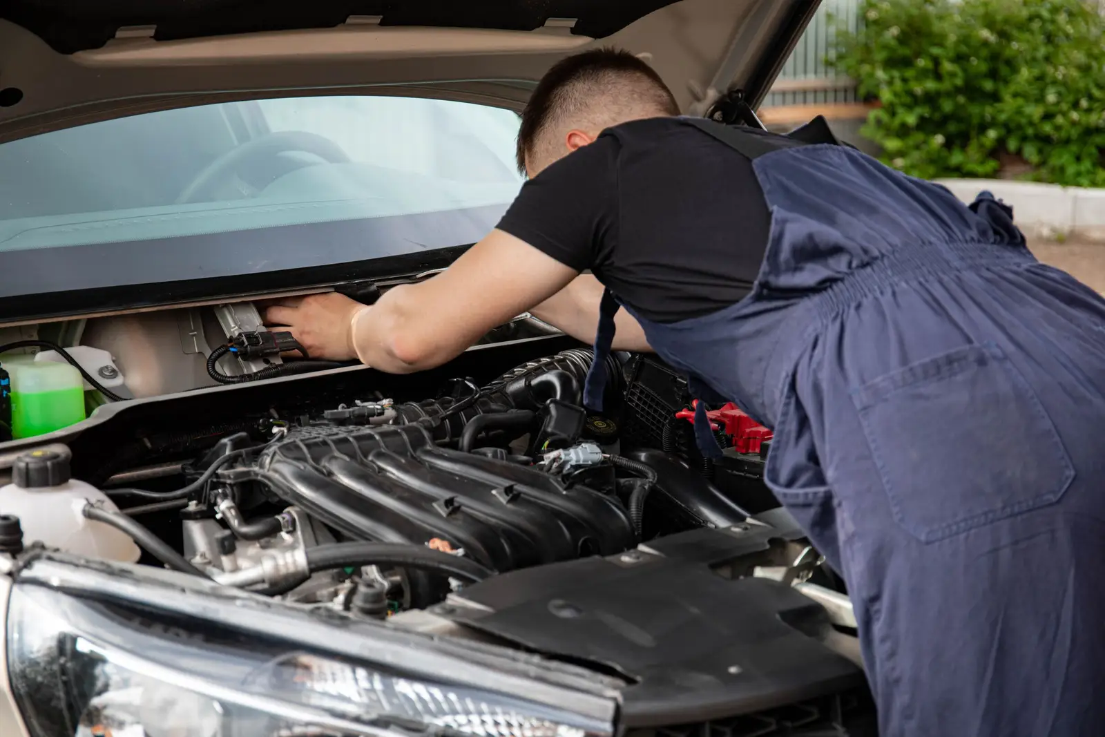 Mechanic leaning into an open engine bay to diagnose a car, representative of auto repair at S & J Auto near Flagstaff