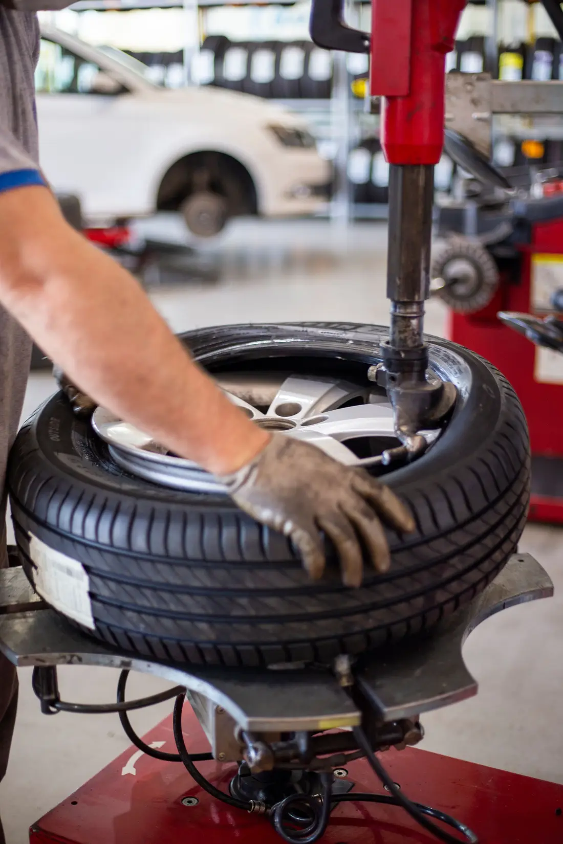 Gloved hand guiding a tire onto a wheel on a tire-changing machine